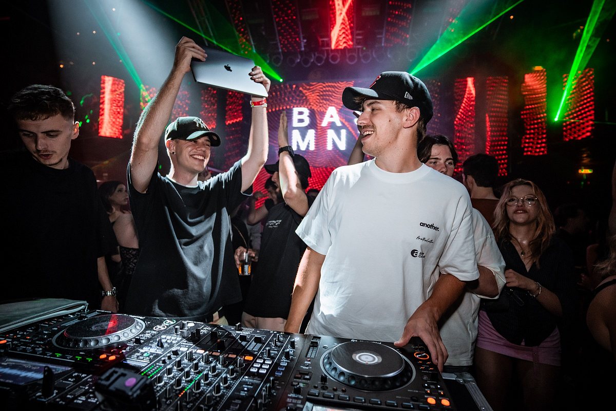 DJ-Pult vor vollem Publikum, farbiges Bühnenlicht